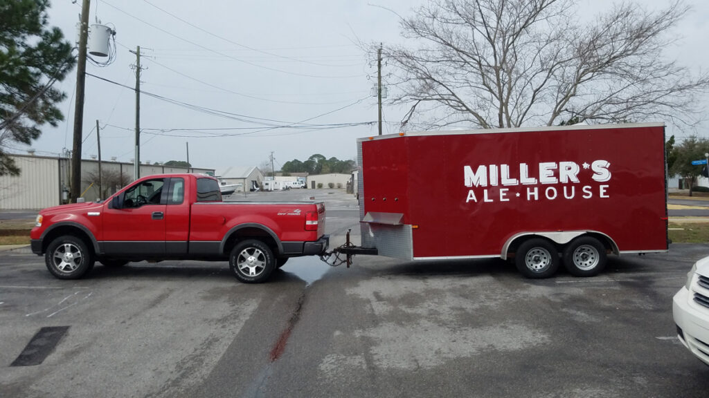 Red truck towing Miller's Ale House trailer