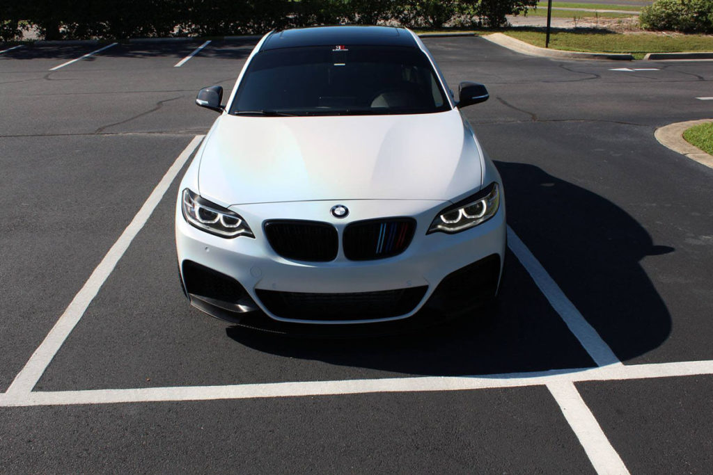 BMW M235 satin white psychedelic wrap with gloss black accents and carbon fiber details.